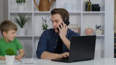 Karantina sırasında dizüstü bilgisayarla çalışan bir adam. Ana ofis ve ebeveynlik. Küçük çocuk gürültü yapıyor, rahatsız ediyor..