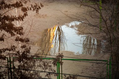 Stadyumdaki yağmurdan sonra büyük su birikintisi. Su, güneş ışığındaki evi yansıtır..