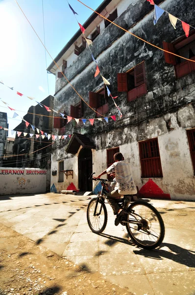 küçük bir çocuğun bisikletini stonecity kırmızı, mavi ve beyaz bayrağı altında eski sokaklarında sürme