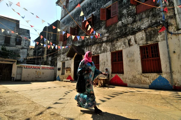 Jonge moslimvrouw wandelen in de vlaggen ingericht straten van stonecity, zanzibar Stockfoto