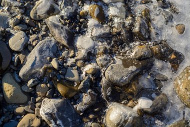 Dağ nehrinde kayaların ve buzların üzerinden akan su