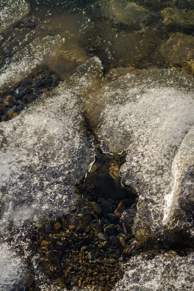 Dağ nehrinde kayaların ve buzların üzerinden akan su