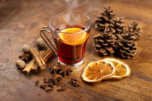 Glühwein met sinaasappel en specerijen op houten achtergrond — Stockfoto