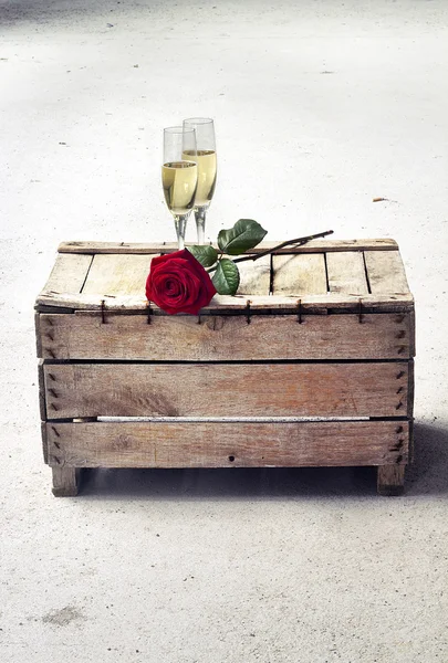 Copos de champanhe e rosa vermelha em uma caixa de madeira — Fotografia de Stock