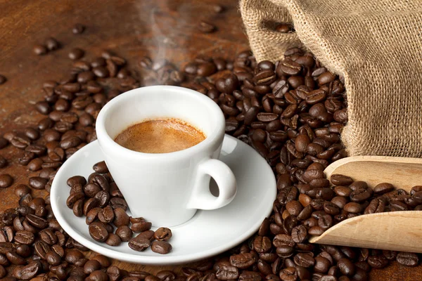 Taza de café con saco de arpillera de frijoles asados y cucharada — Foto de Stock