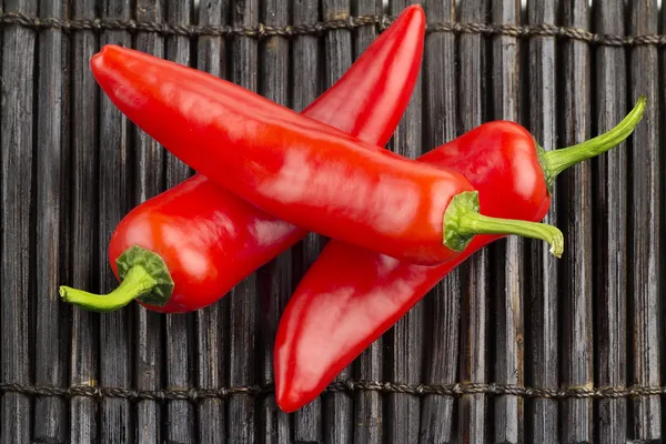 Three fresh chillies on bamboo black mat — Stock Photo, Image