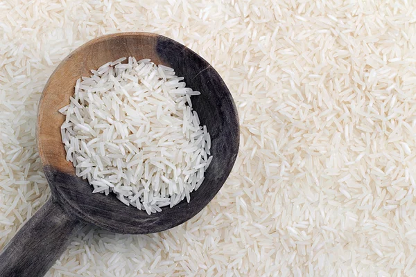 Cuchara de madera con arroz tailandés sobre fondo de granos de arroz —  Fotos de Stock