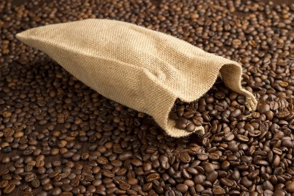 Burlap sack on fresh coffee beans background — Stock Photo, Image