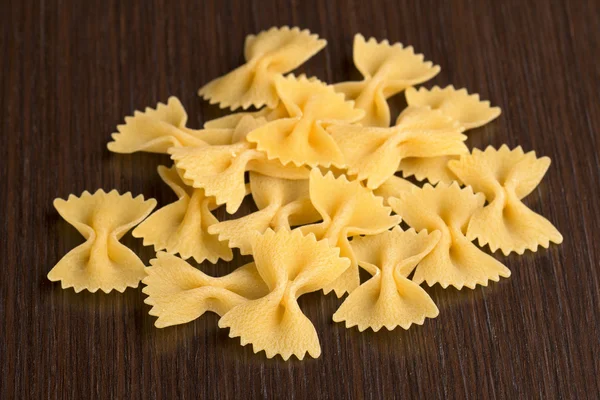 Pile of bow tie pasta on wooden background — Stock Photo, Image