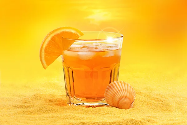 Летний коктейль и раковина гребешка на пляже на закате — стоковое фото