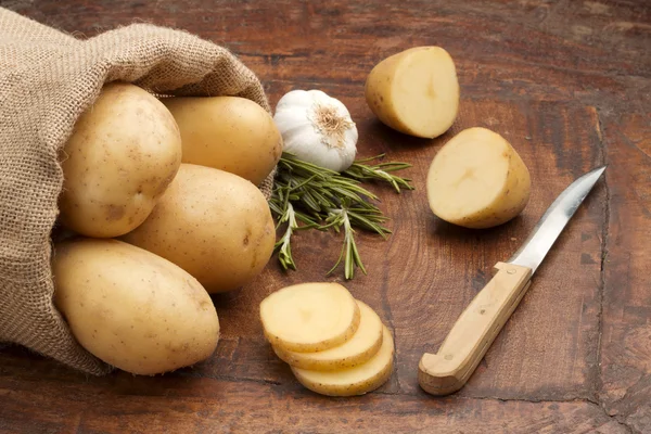 Geschnittene rohe Kartoffeln, Rosmarin und Knoblauchknolle — Stockfoto