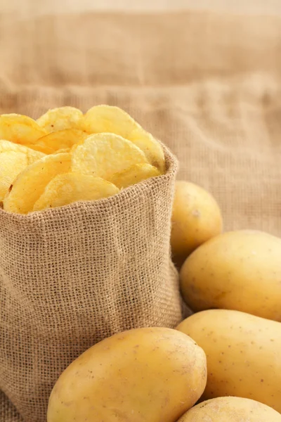 Jutebeutel voller Chips und rohen Kartoffeln — Stockfoto