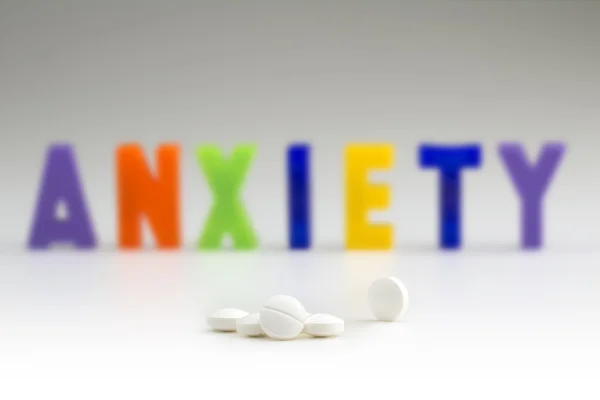 Comprimidos brancos e palavra ansiedade embaçada — Fotografia de Stock