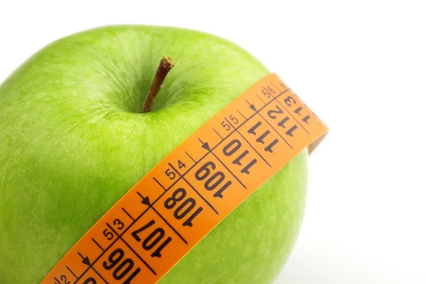 Green apple wrapped by a measuring tape — Stock Photo, Image