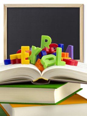 Kitaplar, renkli harfler ve arka planda bir tahta yığını