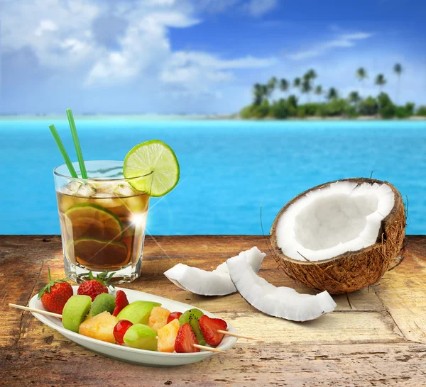 Cuba libre y frutas tropicales sobre una mesa de madera en un paisaje marino polinesio — Foto de Stock