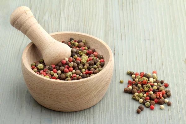 Mortar and pestle with peppercorn mix on wooden table — Stock Photo, Image