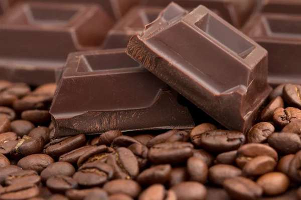 Trozos de chocolate rotos sobre fondo de granos de café — Foto de Stock