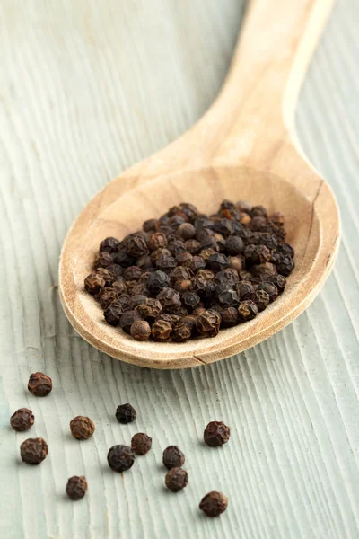 Close up of black pepper in a wooden spoon — Stock Photo, Image
