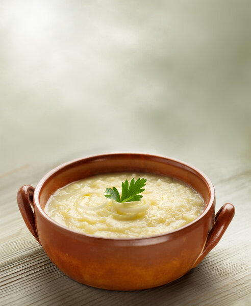 Steaming bowl of potato soup on wooden table