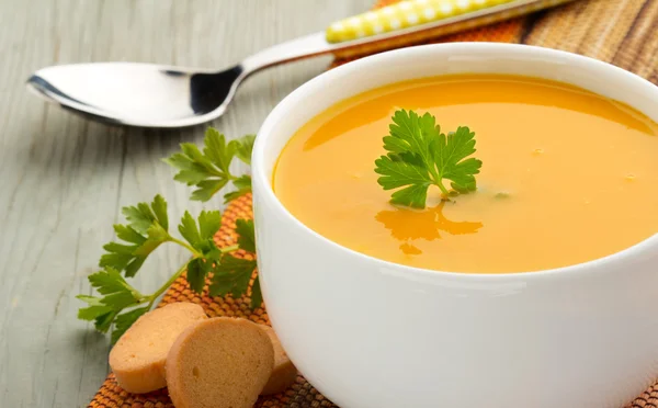 Skål med soppa, persilja och krutonger på träbord — Stockfoto