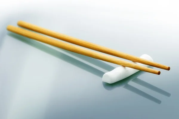 Pair of wooden chopsticks on glass table — Stock Photo, Image