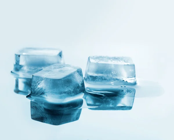 Três cubos de gelo em uma superfície de espelho — Fotografia de Stock