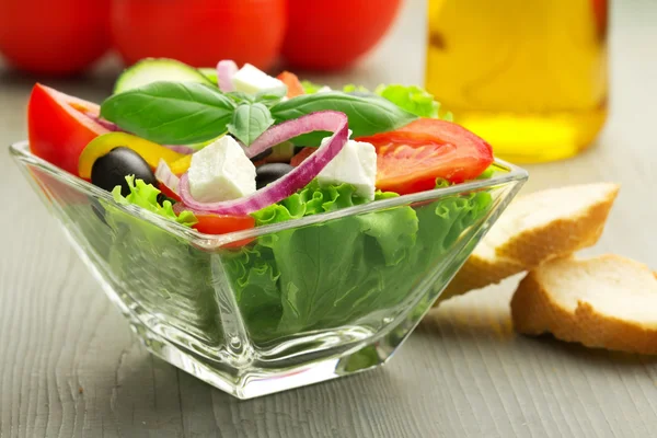 Salade grecque, pain et ingrédients sur table en bois — Photo