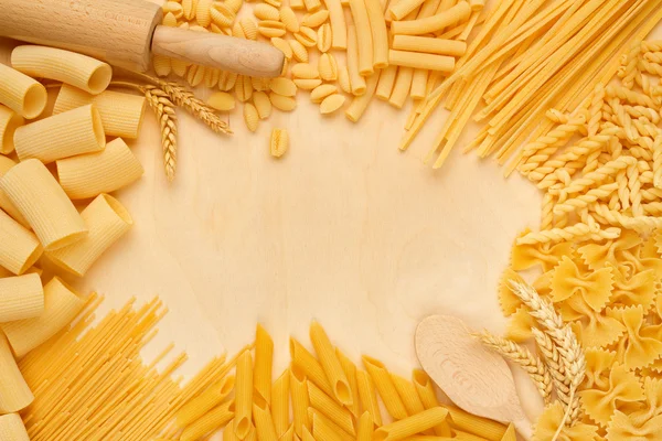 Tipos de pasta y utensilios de cocina sobre mesa de madera — Foto de Stock