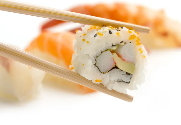 Bambu ätpinnar med Kalifornien uramaki och defocused sushi — Stockfoto