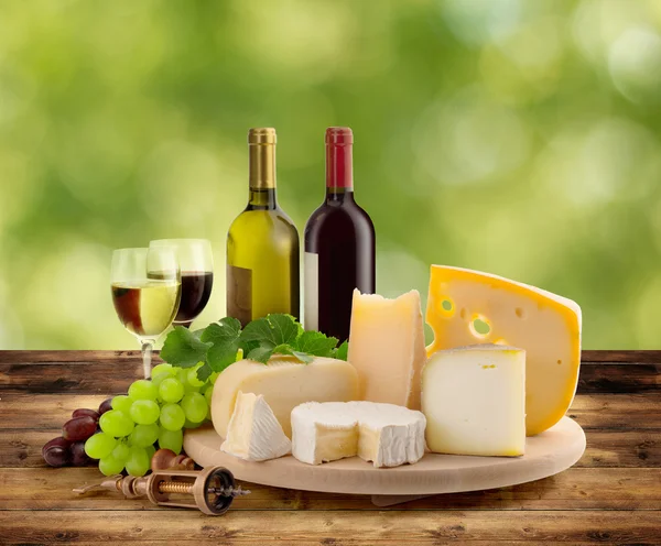 Cheeseboard, grape and wine on wooden table in countryside — Stock Photo, Image