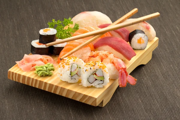 Sushi de frutos do mar japoneses e pauzinhos em placa de madeira — Fotografia de Stock