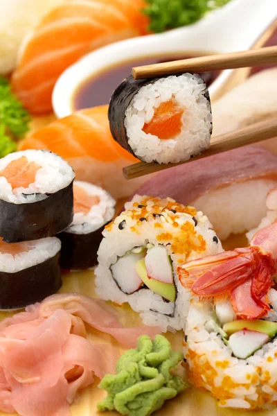 Ätpinnar med sushi maki över en sushi tallrik — Stockfoto