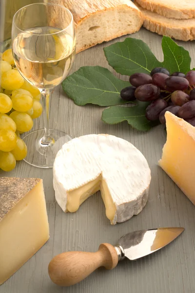 Queijo variado, vinho e pão na mesa de madeira — Fotografia de Stock