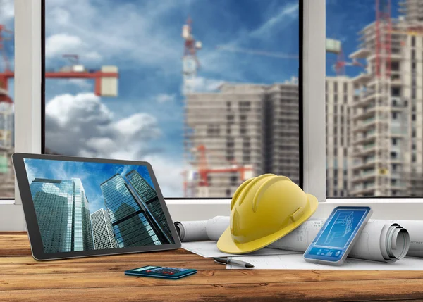 Tablet, smartphone, safety helmet and blueprints in construction site — Stock Photo, Image