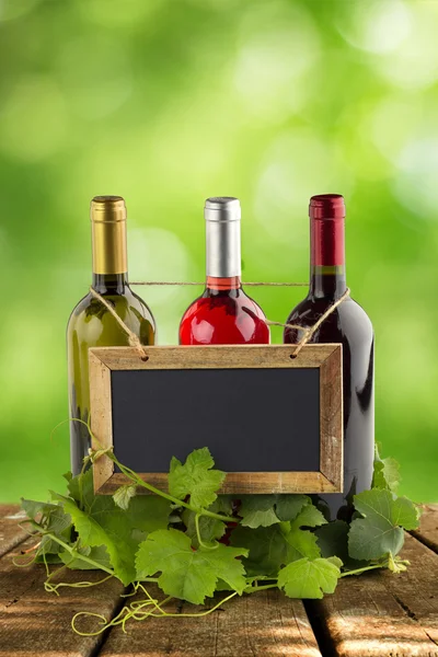 Tableau noir accroché aux bouteilles de vin et aux feuilles de vigne — Photo