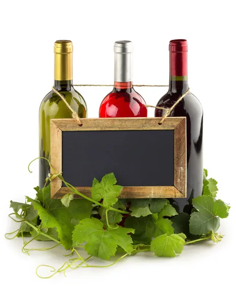 Blackboard hanging on wine bottles and grapevine leaves — Stock Photo, Image