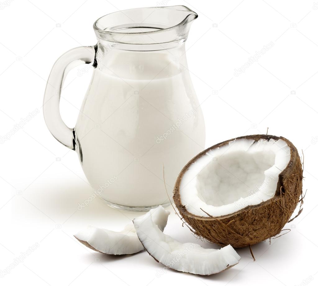 Jug of coconut milk and half coconut on white background