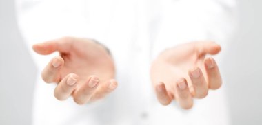 Open empty hands of young woman in white coat isolated. Caregiving and assistance concept