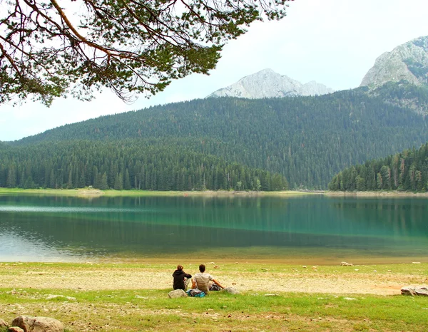 Young people sitting on the bank of the lake — Stock Photo, Image