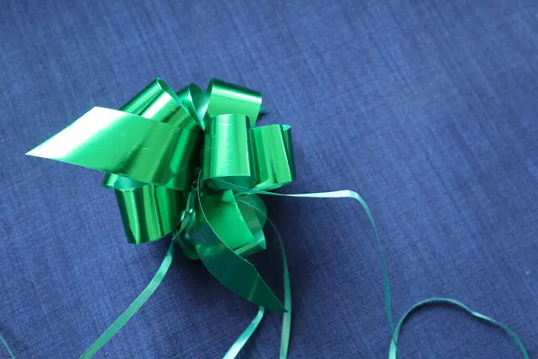 Parlak yeşil bir hediye ile mavi kot kumaş arka plan parlak yeşil yay