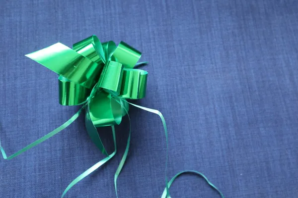 Parlak yeşil bir hediye ile mavi kot kumaş arka plan parlak yeşil yay