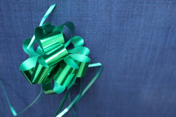 Parlak yeşil bir hediye ile mavi kot kumaş arka plan parlak yeşil yay