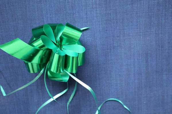 Parlak yeşil bir hediye ile mavi kot kumaş arka plan parlak yeşil yay