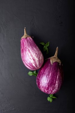 Mor patlıcan ve siyah arka planda yeşil-mor fesleğen. Sağlıklı beslenme. Vejetaryen yemeği. Organik yiyecekler. 