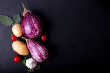 Mor patlıcan ve siyah arka planda yeşil-mor fesleğen. Sağlıklı beslenme. Vejetaryen yemeği. Organik yiyecekler. 