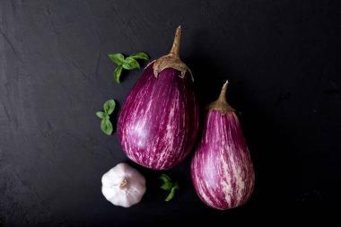 Mor patlıcan ve siyah arka planda yeşil-mor fesleğen. Sağlıklı beslenme. Vejetaryen yemeği. Organik yiyecekler. 