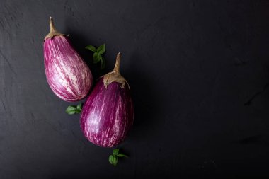 Mor patlıcan ve siyah arka planda yeşil-mor fesleğen. Sağlıklı beslenme. Vejetaryen yemeği. Organik yiyecekler. 