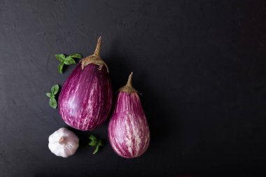 Mor patlıcan ve siyah arka planda yeşil-mor fesleğen. Sağlıklı beslenme. Vejetaryen yemeği. Organik yiyecekler. 