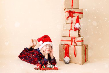 Noel şapkalı ve noel hediyeli küçük çocuk. Tebrik kartı. Kış tatili kavramı.